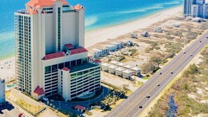 A high-rise hotel with a central courtyard, a beach view, and a road running parallel to the beach. - Phoenix West 2107 | Orange Beach, AL (Orange Beach)