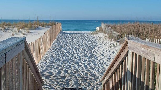 A wooden boardwalk leading to a beach with sand and sparse vegetation. - Luxurious Condo with Beach Access and Ocean Views (Destin)