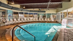 A large indoor swimming pool with clear blue water, surrounded by lounge chairs and a bar area. - Luxurious Condo with Beach Access and Ocean Views (Destin)