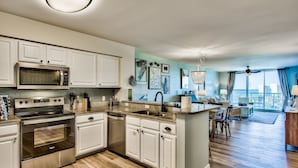 A modern kitchen with stainless steel appliances, white cabinetry, and a large island. - Luxurious Condo with Beach Access and Ocean Views (Destin)