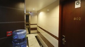 A hotel corridor with a water dispenser, a fire alarm, and a door marked with the number 802. - Garden Hotel (Kowloon)