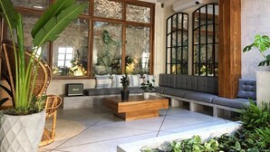A modern living room with a large window, a wooden coffee table, a grey sofa, and a potted plant. - Casa San Antonio, Designer Villa w / Rooftop Pool. (Cartagena)
