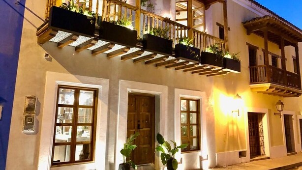 A building with a wooden balcony, potted plants, and a door. - Casa San Antonio, Designer Villa w / Rooftop Pool. (Cartagena)