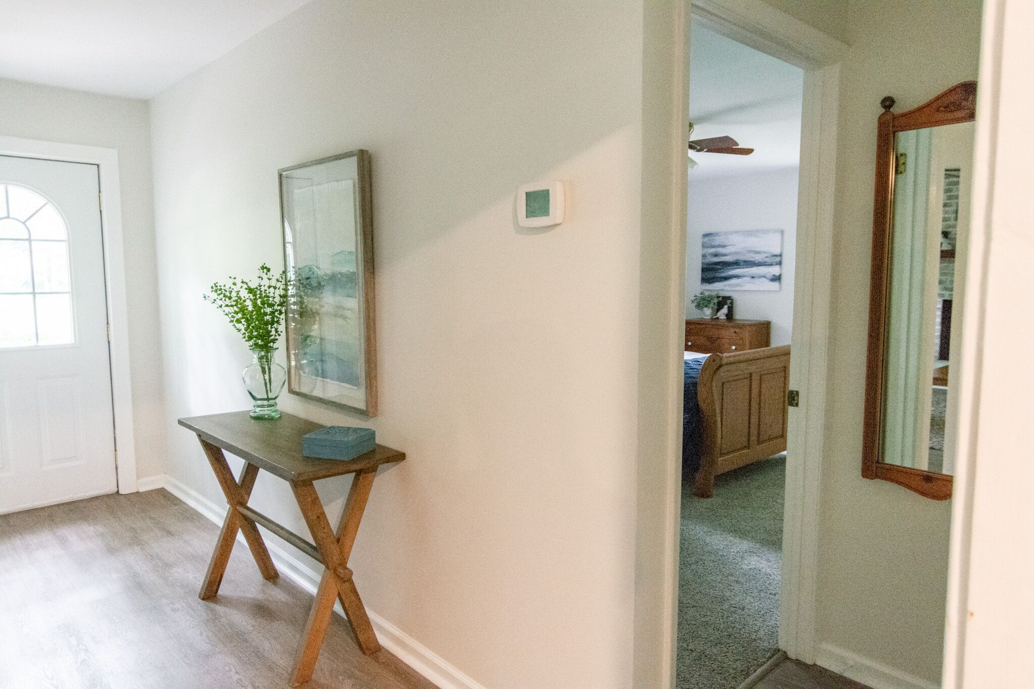 A hallway with a wooden table, a framed picture, and a small plant.
