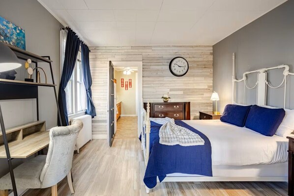 Un dormitorio con cama, escritorio, silla, reloj y radiador.
