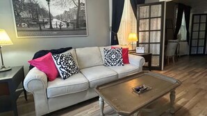 A living room with a sofa, coffee table, and a painting on the wall.