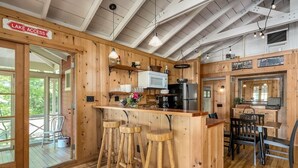 L’intérieur d’un chalet en bois comprend un coin cuisine avec un bar, des tabourets et une table à manger.