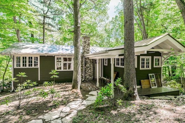 A rustic cabin with a stone chimney, surrounded by trees and a stone pathway. - THREE COTTAGE FAMILY COMPOUND - Hot Tub + Fire Pit with water/downtown views (Saugatuck)