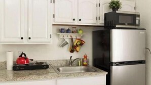 A kitchen with white cabinets, a stainless steel refrigerator, a microwave, a kettle, and a sink. - 1 Bedroom Apt near Coconut Grove (Miami)