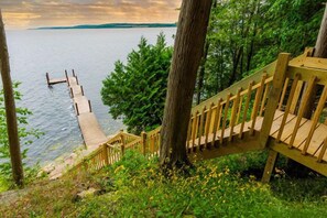 A wooden staircase leading down to a dock over water, surrounded by trees. - Door County Waterfront Lodge with Private Pier (Sturgeon Bay)