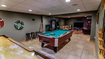 Ein Billardtisch in einem Raum mit grüner Wand, ein Billardtisch im Vordergrund und ein Barbereich im Hintergrund.