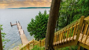 A wooden staircase leading down to a dock by a lake, surrounded by trees. - Fully Loaded Lakefront Lodge w/ Pier & Game Room (Sturgeon Bay)