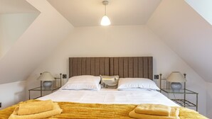 Un dormitorio con cama, dos mesitas de noche y una lámpara en el techo.