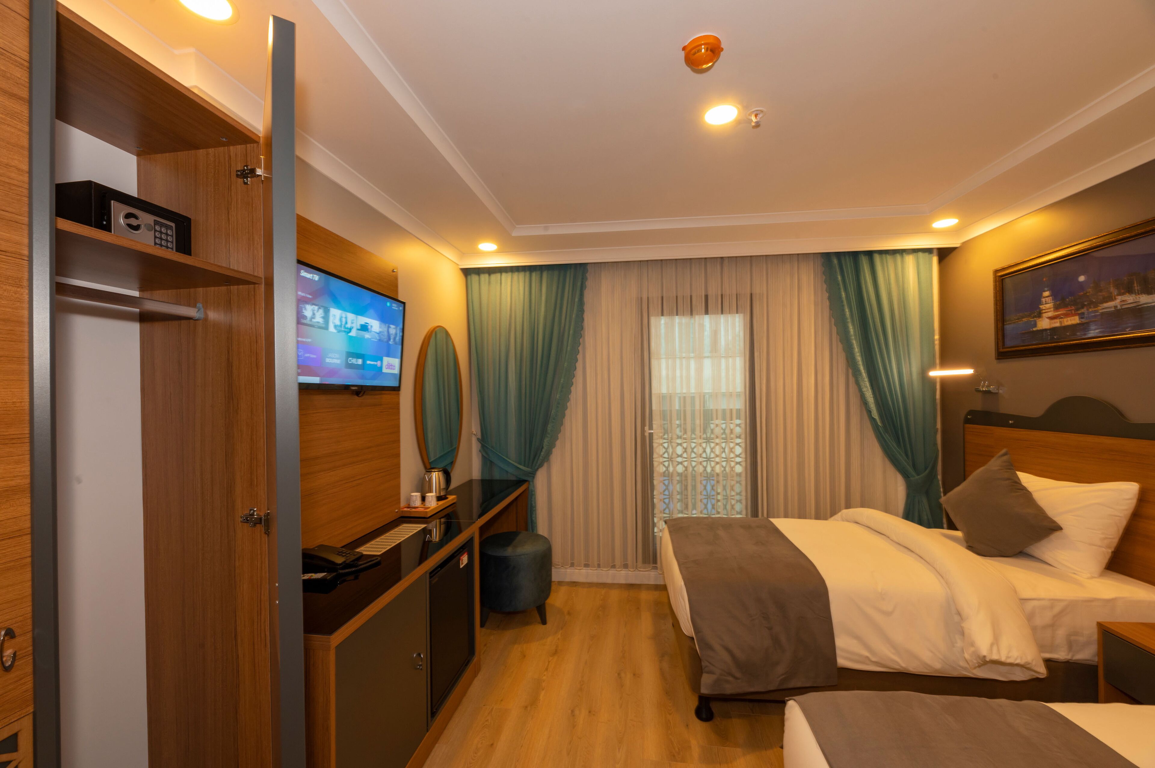 A hotel room with a bed, a desk, a television, and a window with curtains.