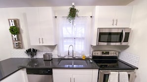 Une cuisine moderne avec des meubles blancs, un lave-vaisselle en acier inoxydable, un four double et un four à micro-ondes.
