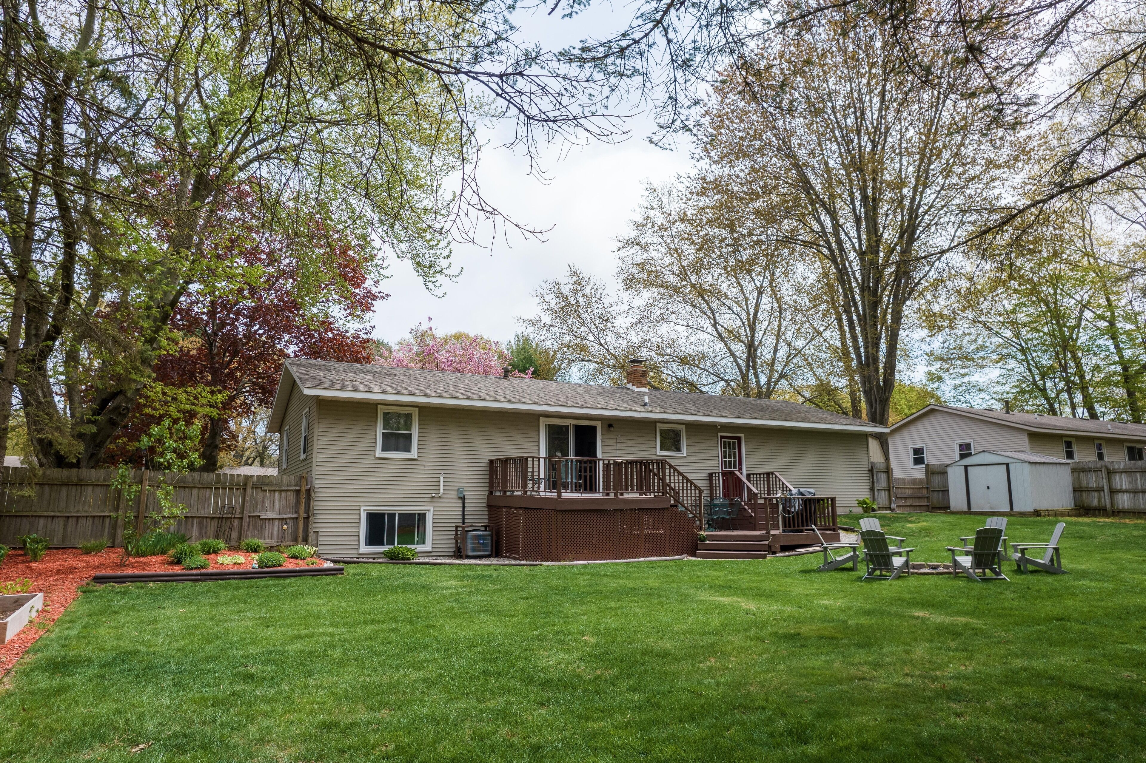 A two-story house with a covered patio, a fenced yard, and a small shed.