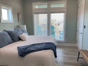 Un dormitorio con cama, un banco, un armario y una ventana con persianas.