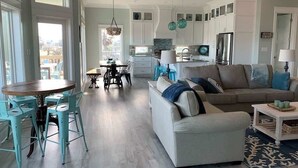 A spacious living area with a sofa, coffee table, and dining table with chairs. - St. Somewhere, Dog Friendly (Crystal Beach)
