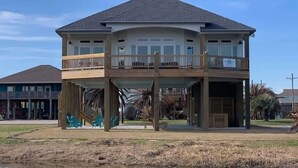 A two-story house with a balcony, a covered porch, and a pond in front. - St. Somewhere, Dog Friendly (Crystal Beach)