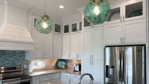 A modern kitchen with white cabinetry, stainless steel appliances, and a marble countertop. - St. Somewhere, Dog Friendly (Crystal Beach)