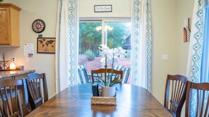 A dining area with a wooden table, chairs, a world map, a clock, and a sign that says "Be Our Guest". - Spacious Townhome in Kanab! Near Zion, Bryce, and more! Pool and Hot Tub. Sleeps 8! (Kanab)