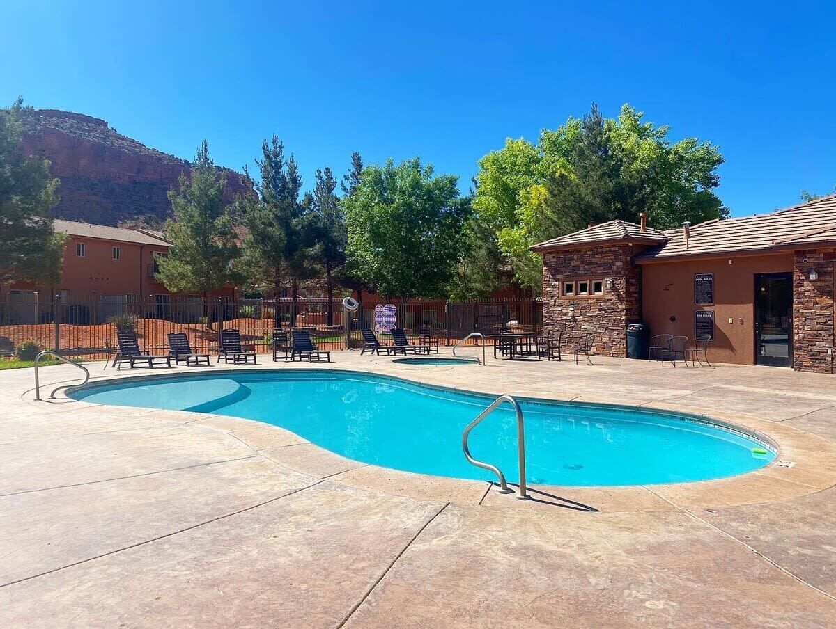 A swimming pool with lounge chairs and a stone building in the background.
