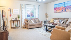 A living room with two sofas, a coffee table, a TV, and a ceiling fan. - Spacious Townhome in Kanab! Near Zion, Bryce, and more! Pool and Hot Tub. Sleeps 8! (Kanab)