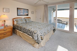 Relax in this serene bedroom with a large bed, nightstand, and picture on the wall, plus a sliding door to a balcony.