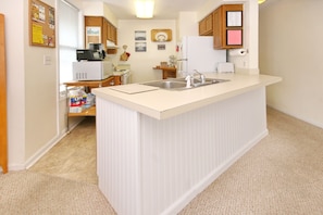 Compact kitchen with central island, sink, and standard appliances.