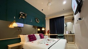 Een hotelkamer met een bed, nachtkastje, televisie en een bureau met stoel.