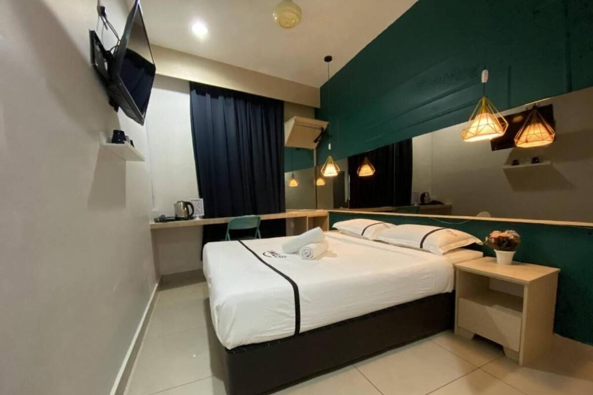 A modern hotel room with a bed, bedside tables, a desk, and a large mirror.