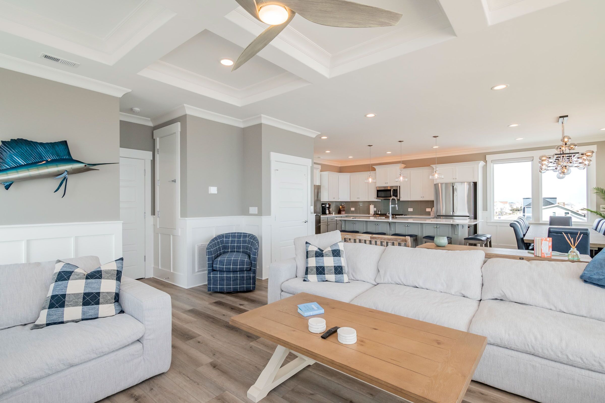 A modern living room with a sofa, a wooden coffee table, and a kitchen in the background.