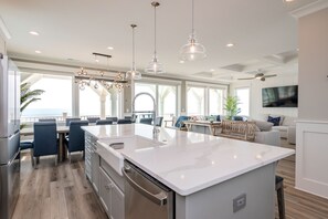 A modern kitchen with a large island, stainless steel appliances, and pendant lighting. - Saltwater Blessing: Beautiful Oceanfront Home with Private Pool, Elevator and Gr (Oak Island)