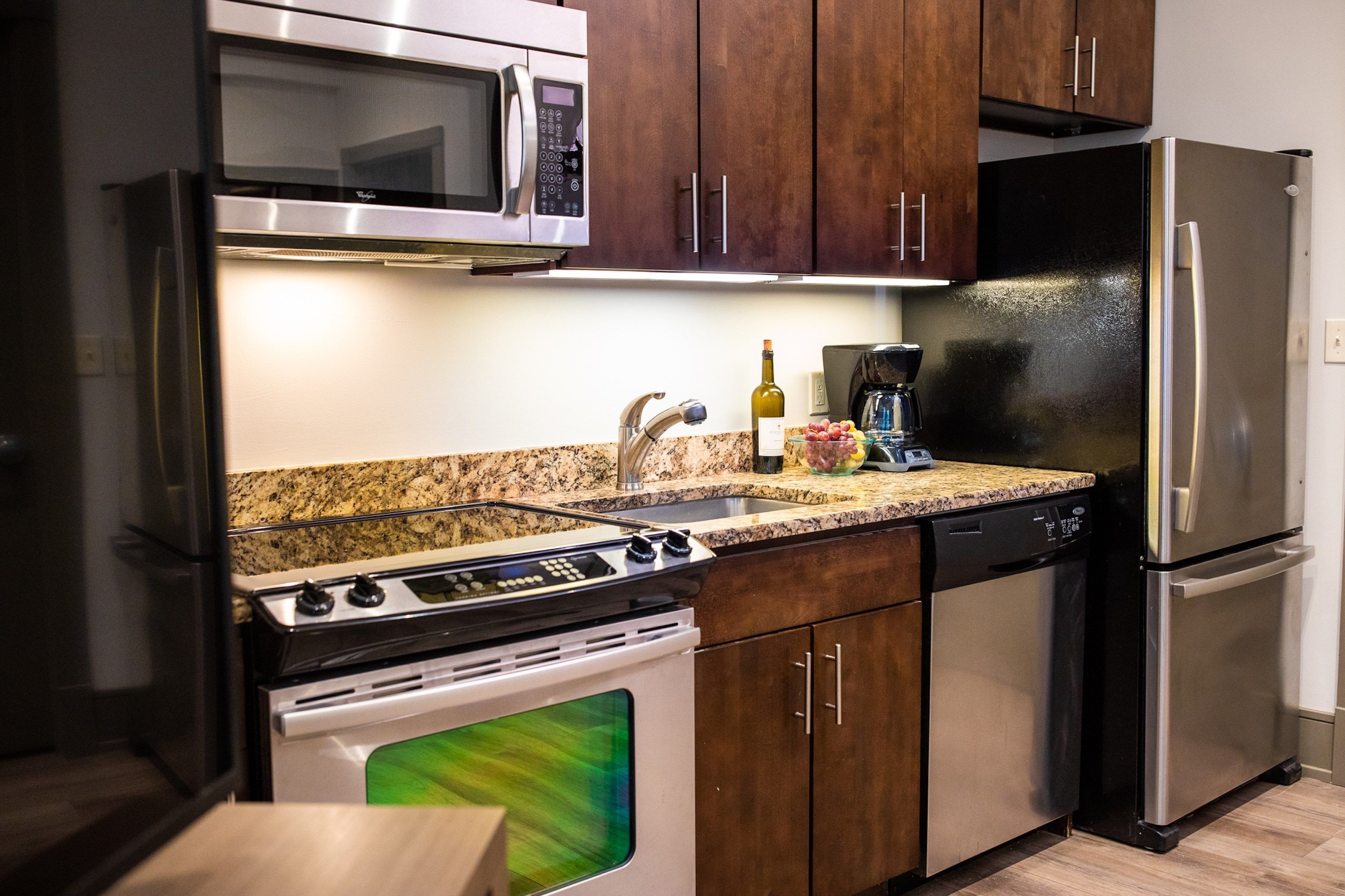 Une cuisine équipée d’appareils électroménagers en acier inoxydable, de plans de travail en granit et d’armoires en bois.