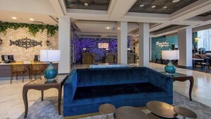 En lobby med en blå sofa, en receptionsdisk og en væg med et skilt, der står "Vacation Station".