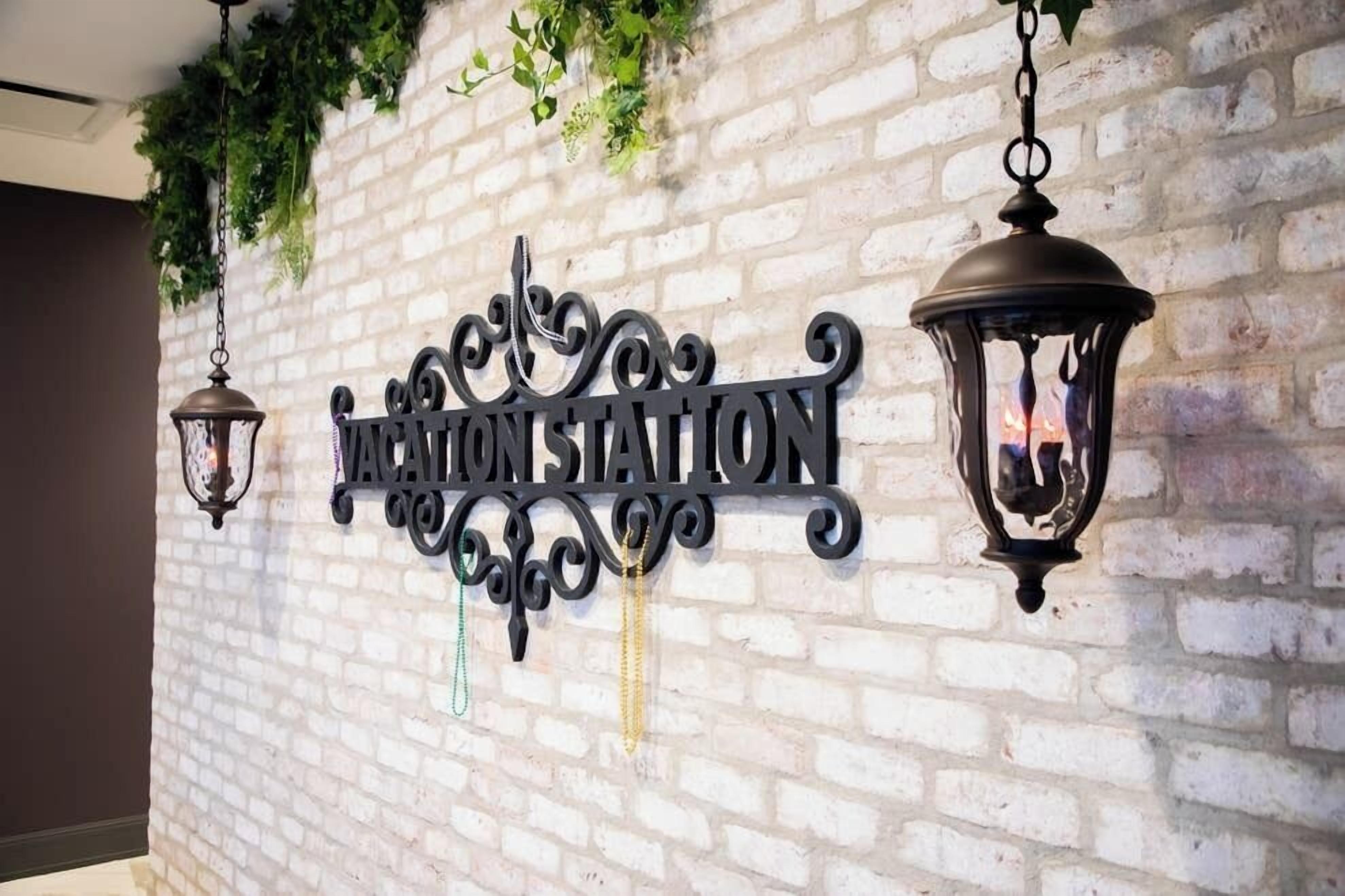 Una pared con un letrero que dice "ACATON STATION" y dos faroles colgantes.