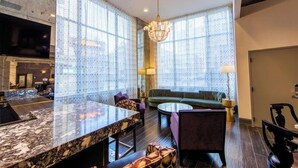 A spacious living area with a large window, a chandelier, a sofa, and a coffee table. - 2 Bedroom Villa with Air-Conditioning (New Orleans)