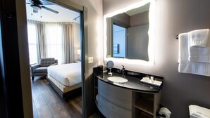 Un baño de hotel moderno con un espejo grande, un lavamanos y un inodoro.