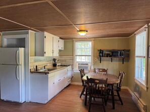 A kitchen with a refrigerator, stove, microwave, and wooden dining table with chairs.