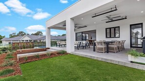 A modern house with a covered patio, outdoor seating, and a swimming pool.