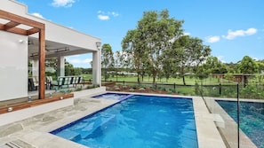 A modern outdoor pool area with a clear view of a golf course in the background.