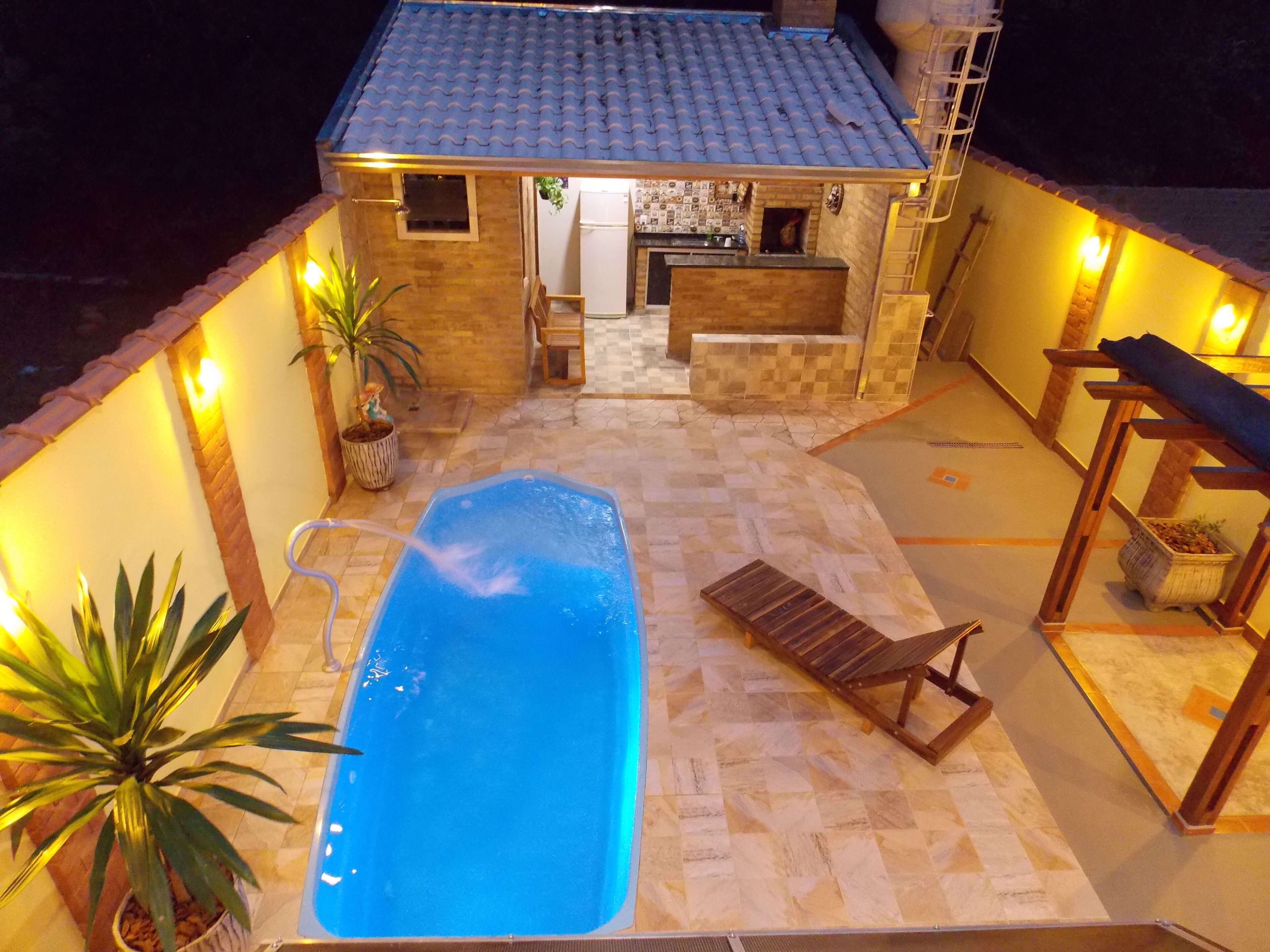 A swimming pool with a wooden deck, a small bar area, and potted plants.