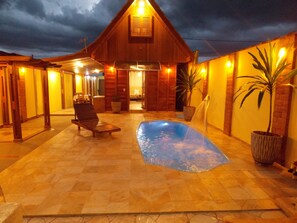 A wooden cabin with a swimming pool, lounge chairs, and potted plants. - Chalet Paradise Brotas SP - Private Pool + Air Conditioning (SP)