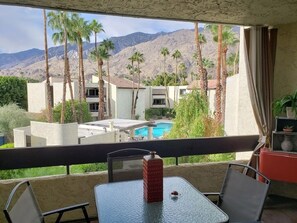 Ein Balkon mit Blick auf einen Pool, Palmen und Berge.