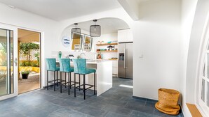 Una cocina moderna con una isla central, taburetes de bar y un refrigerador.