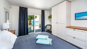 Habitación de hotel con cama, escritorio, silla, televisor y vista a la playa.