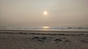 A beach with a sunset, calm waves, and a person walking. - Spacious Beach Villa - Ocean Views - 3 Minute Walk to Shore - Available All Year (Wells)