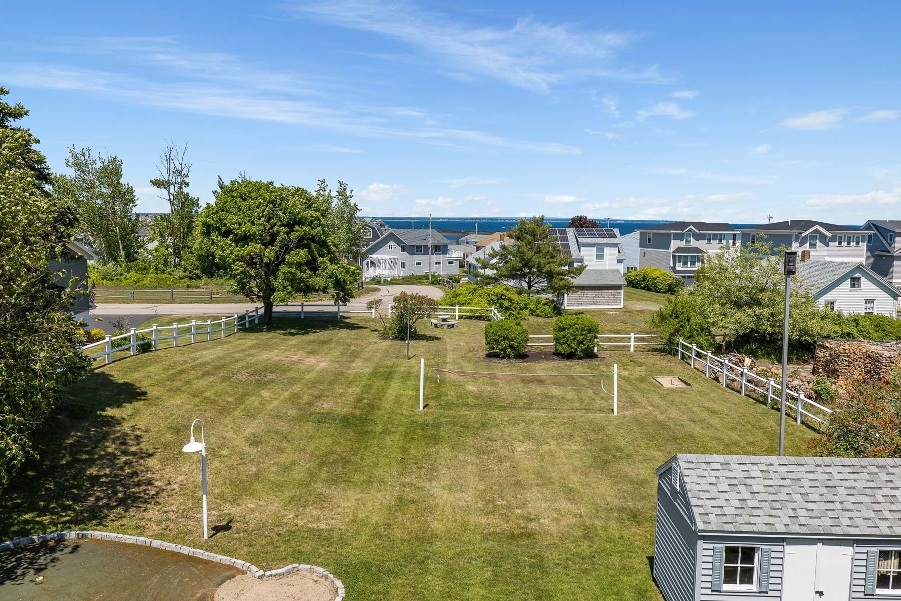 A residential area with houses, a grassy yard, and a view of the sea.