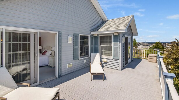A two-story house with a balcony, a bedroom with a sliding glass door, and a small porch area. - Spacious Beach Villa - Ocean Views - 3 Minute Walk to Shore - Available All Year (Wells)
