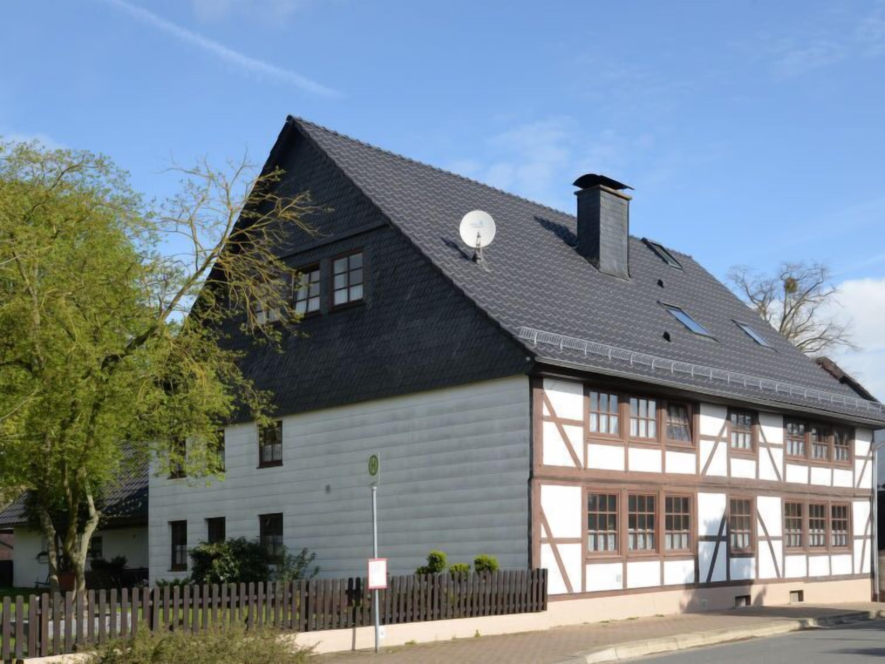 A traditional half-timbered house with a steeply pitched roof, a chimney, and a satellite dish.